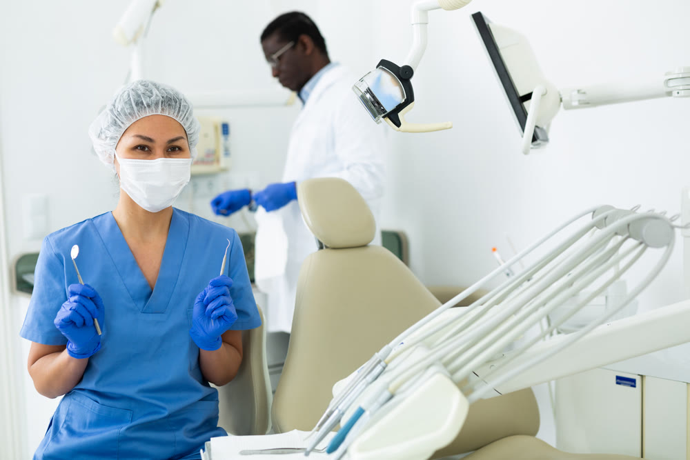 Portrait of a nurse with tools in her hands and wearing a medical mask in dental office