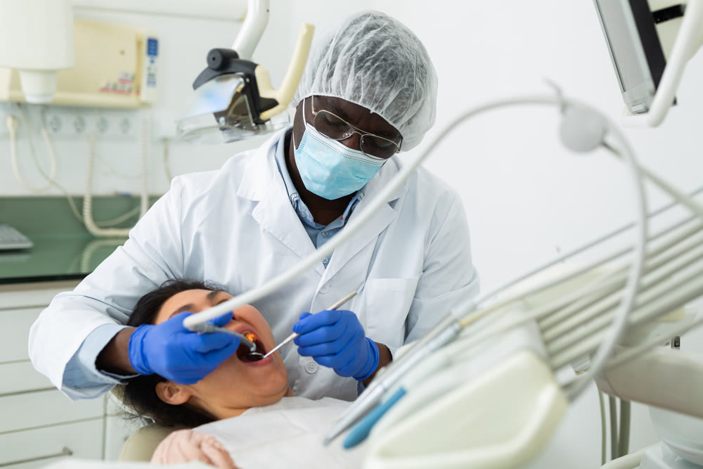 Focused stomatologist treating teeth to female patient in dental office