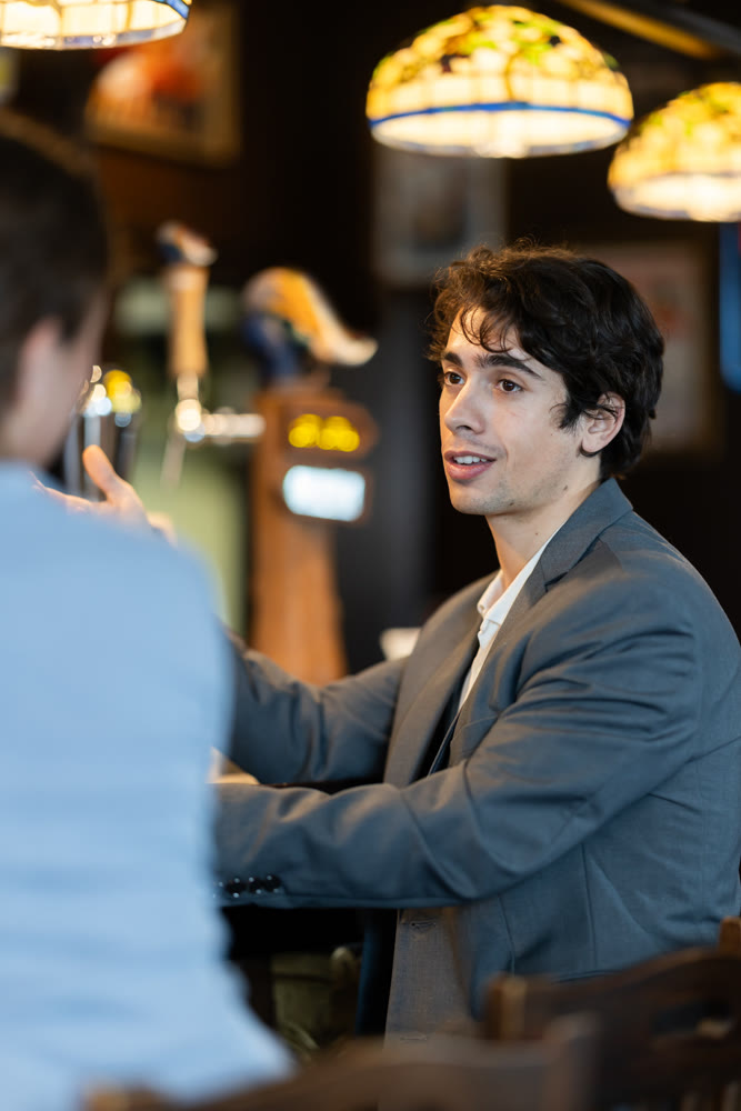 Young man drinking beer and chatting with woman at bar