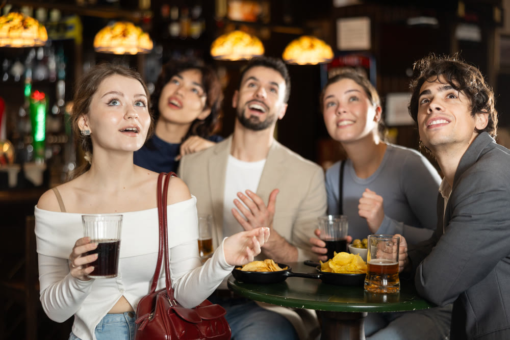 Group of friends watching sports match at bar