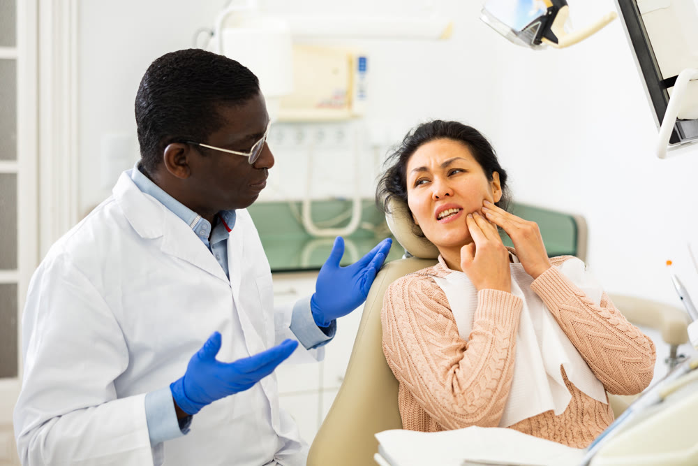Asian woman with toothache sitting in chair at dentist appointment
