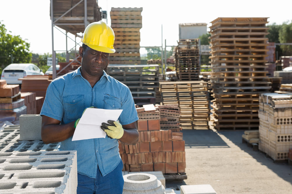 Worker filling documentation beside hollow block stack outdoors