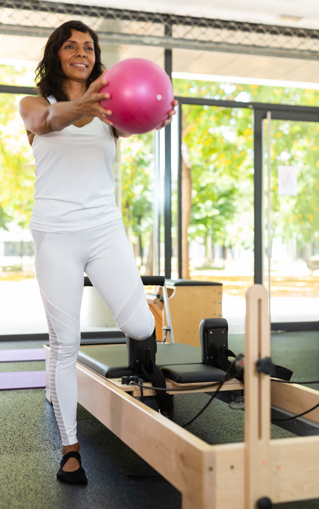 Portrait of positive hispanic woman practicing with pilates bender ball