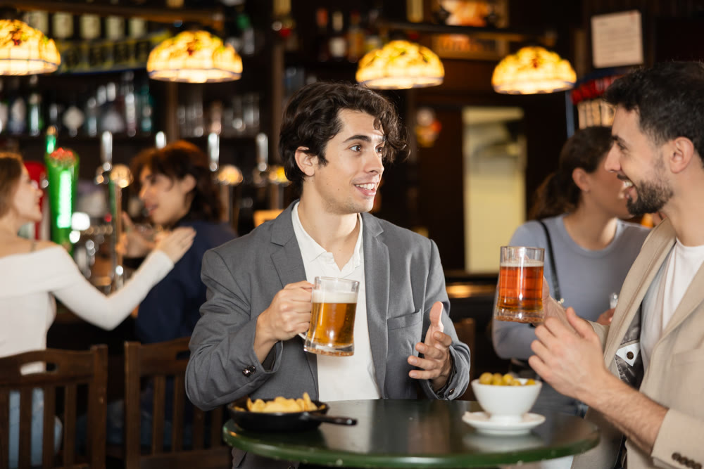 Two young men chatting and drinking beer at bar