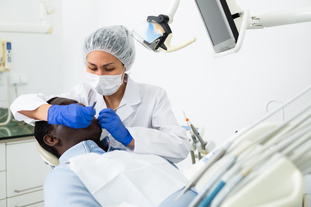 Woman stomatologist treating teeth to patient in dental office