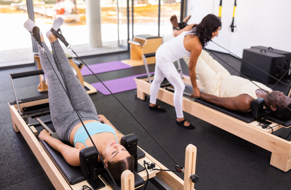 Woman performing set of pilates exercises on reformer in modern fitness studio