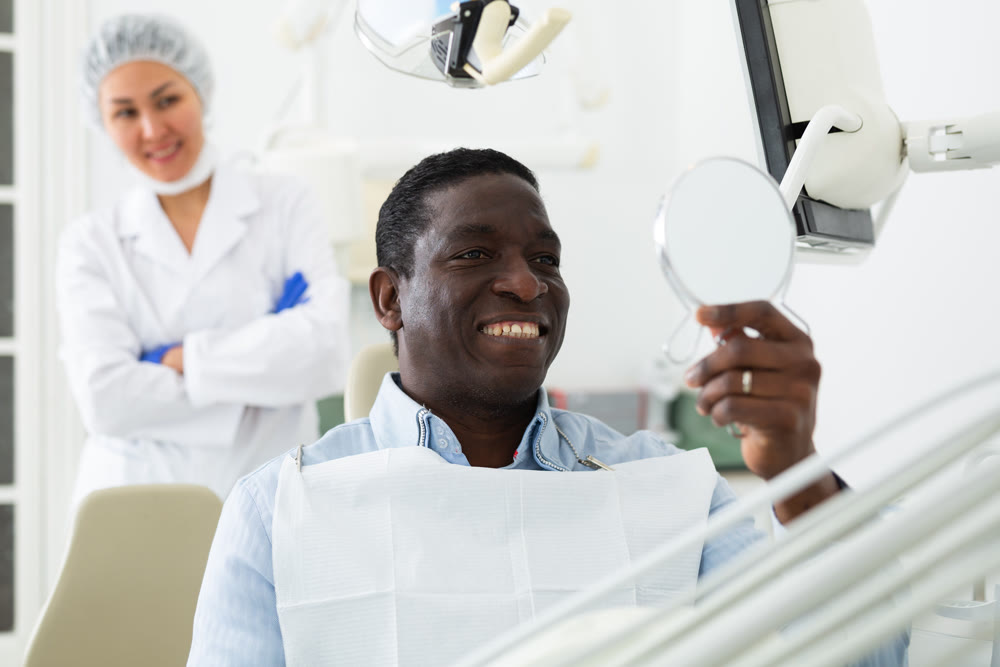African american patient checks cured teeth with mirror