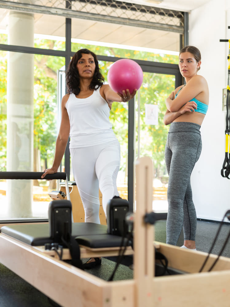 Portrait of positive hispanic woman practicing with pilates bender ball