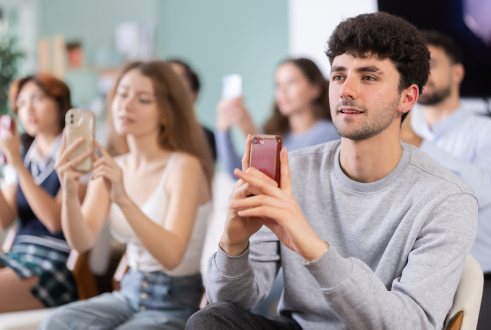 Young guy using mobile phone to scan QR code during interactive lesson