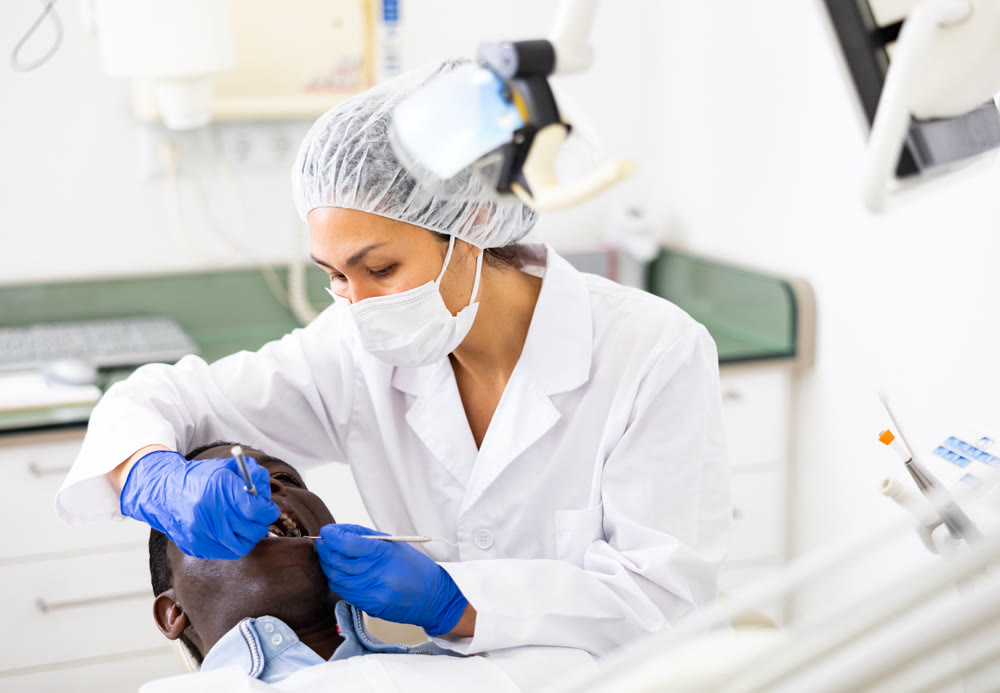 Dentist examining oral cavity of man in dental clinic