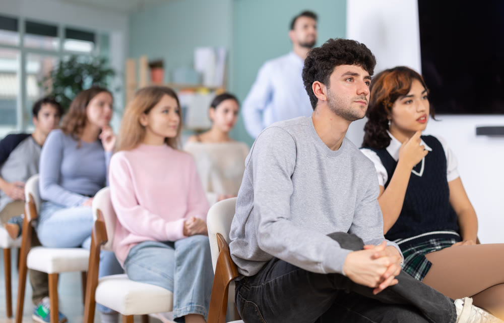 Young guy listening during seminar in a modern classroom
