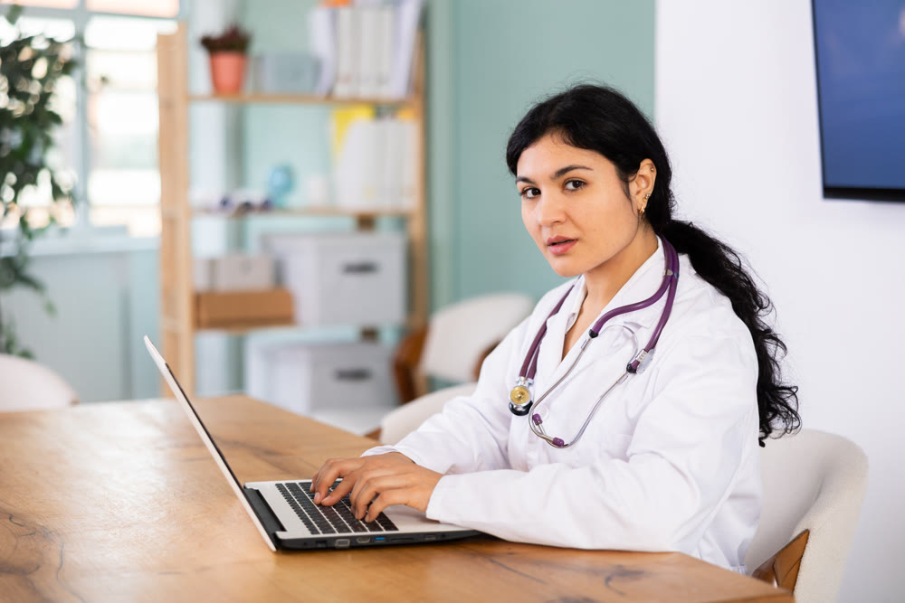 Female doctor works on laptop in room