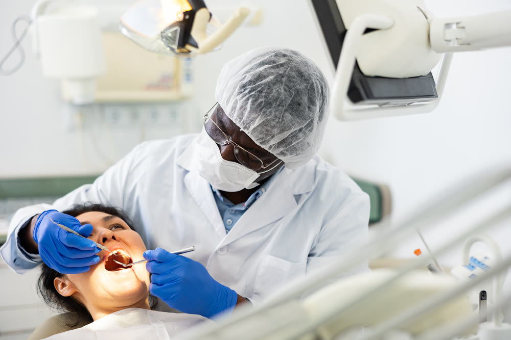Male dentist using tools for tooth repairing on woman patient