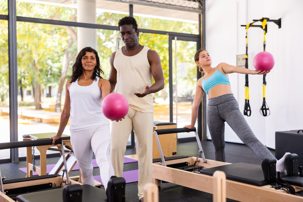 Female trainer controlling movements of woman and man doing pilates