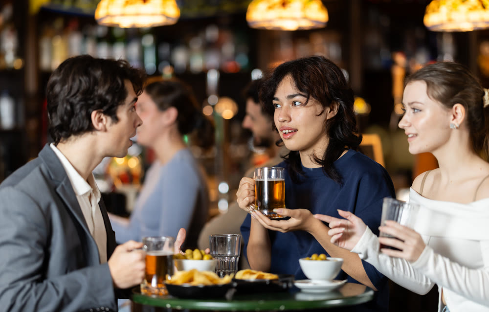 Group of happy friends in bar, drinking beer and having conversation