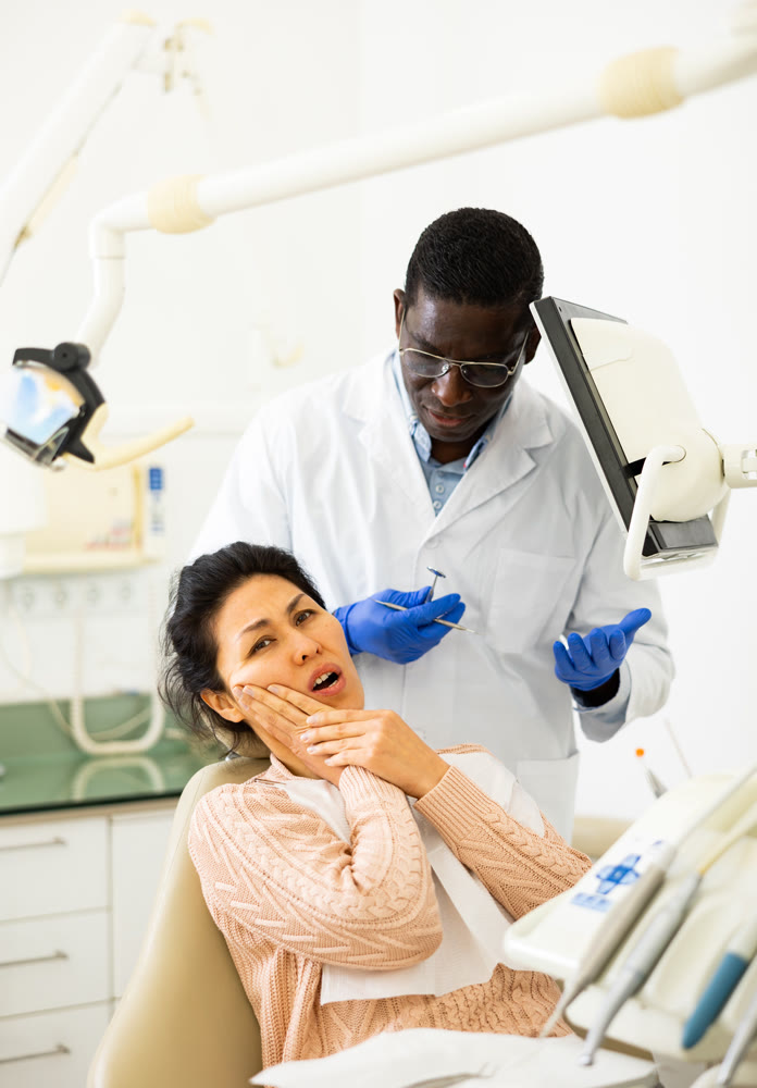 Woman patient complaining to male dentist about toothache at dental clinic