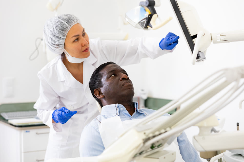 Man patient and woman dentist looking at monitor during consultation