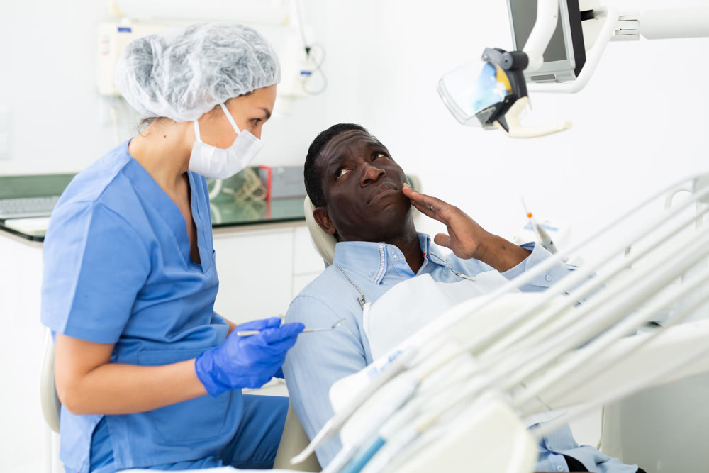 Man complaining about toothache to female dentist