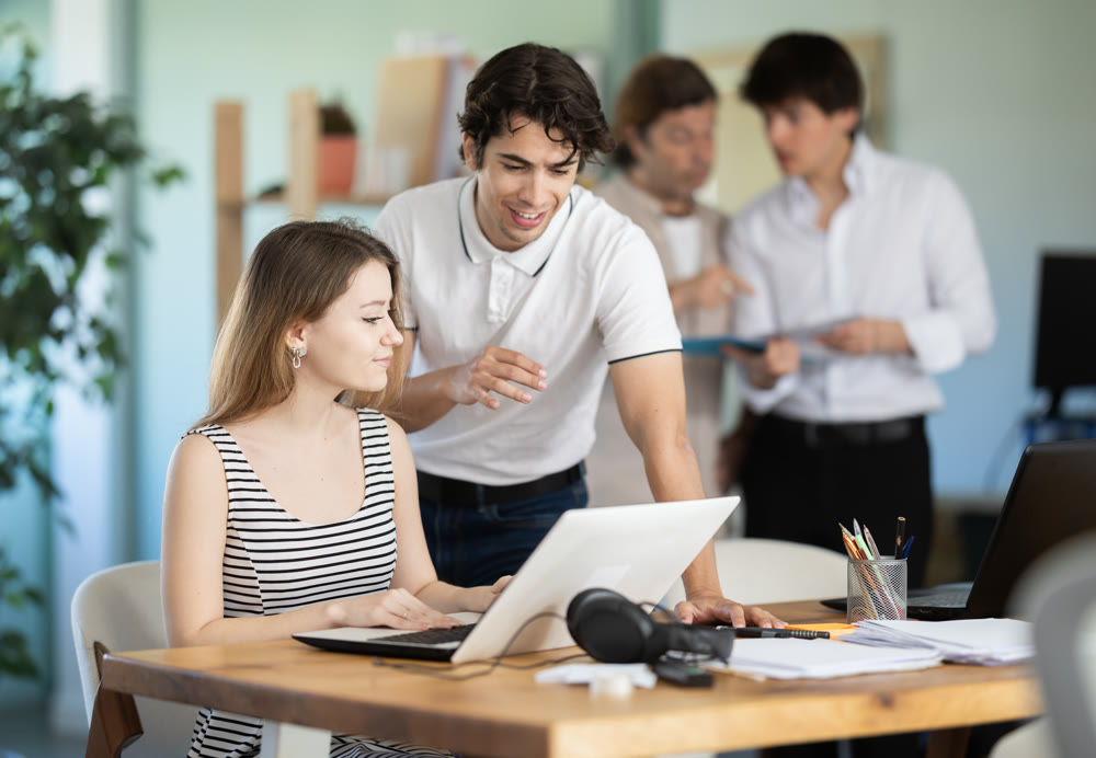 Guy helps girl complete task on laptop