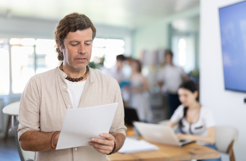 Portrait of manager reading and signing documents in modern office