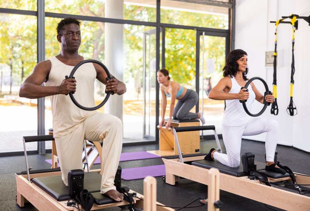 Healthcare professional helps an man restore health with gymnastic ring in pilates class