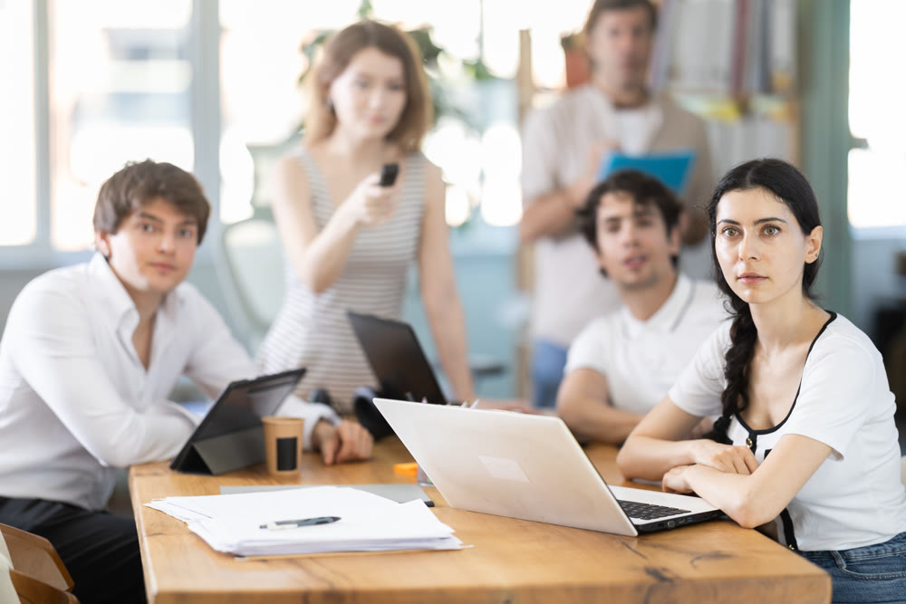 Portrait of group of young businessmen at table watching presentation with interest during business meeting