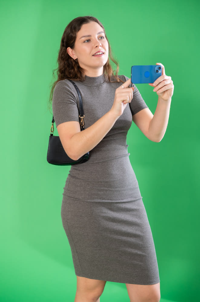 Happy girl scans QR code or takes photo with a smartphone. Green background. Chroma key compositing