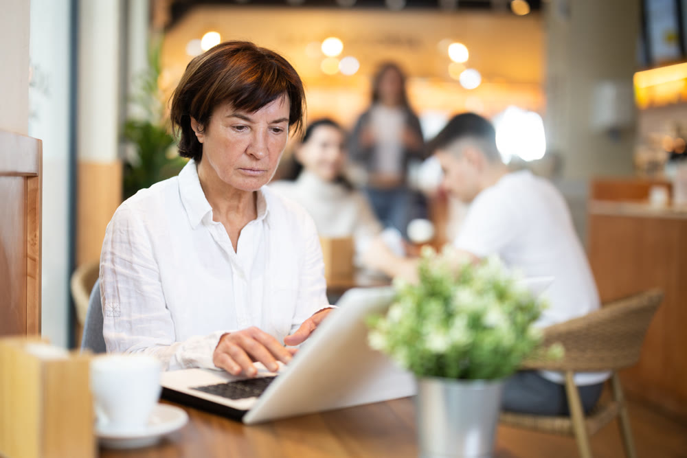 Mature woman sitting at table and typing on a music book