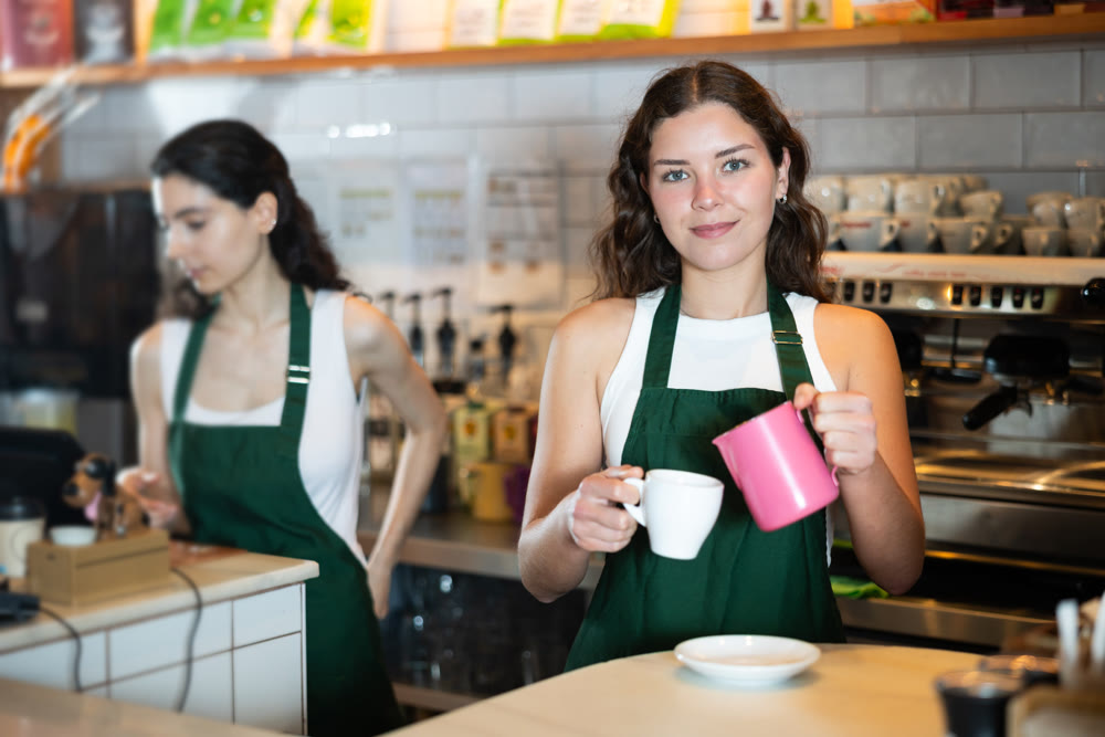 Girl cafe worker pours coffee from cezve coffee pot into cup