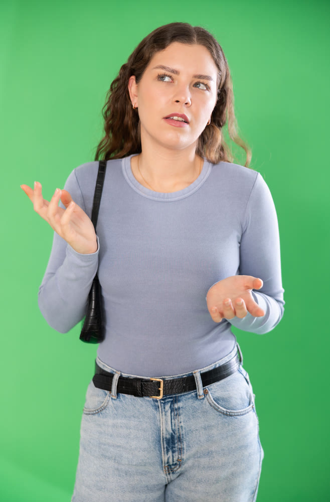 Thoughtful girl expresses bewilderment or forgetfulness on green background