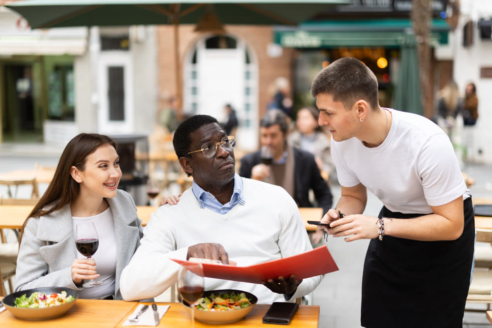 Interethnic couple having lunch in a restaurant and ordering food