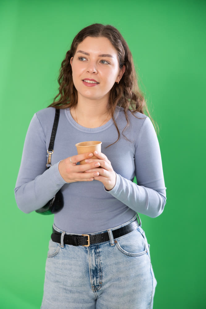 Chroma key compositing. Pretty girl drinking coffee against green chroma key background