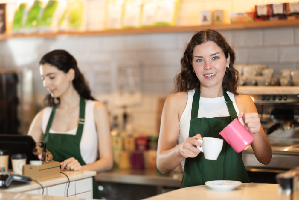 Young woman pouring coffee in cafe