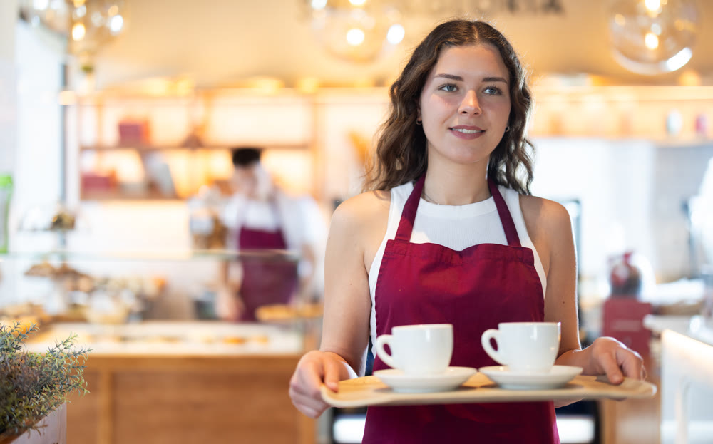 Girl cafe worker carries tray with coffee