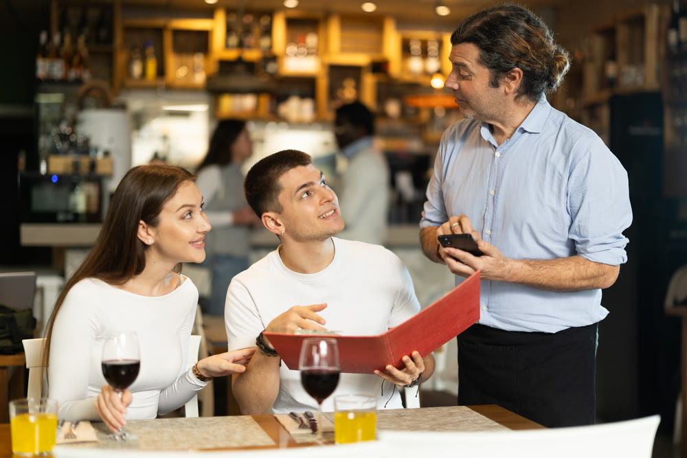 Man listen to restaurant couple customer, writes down order