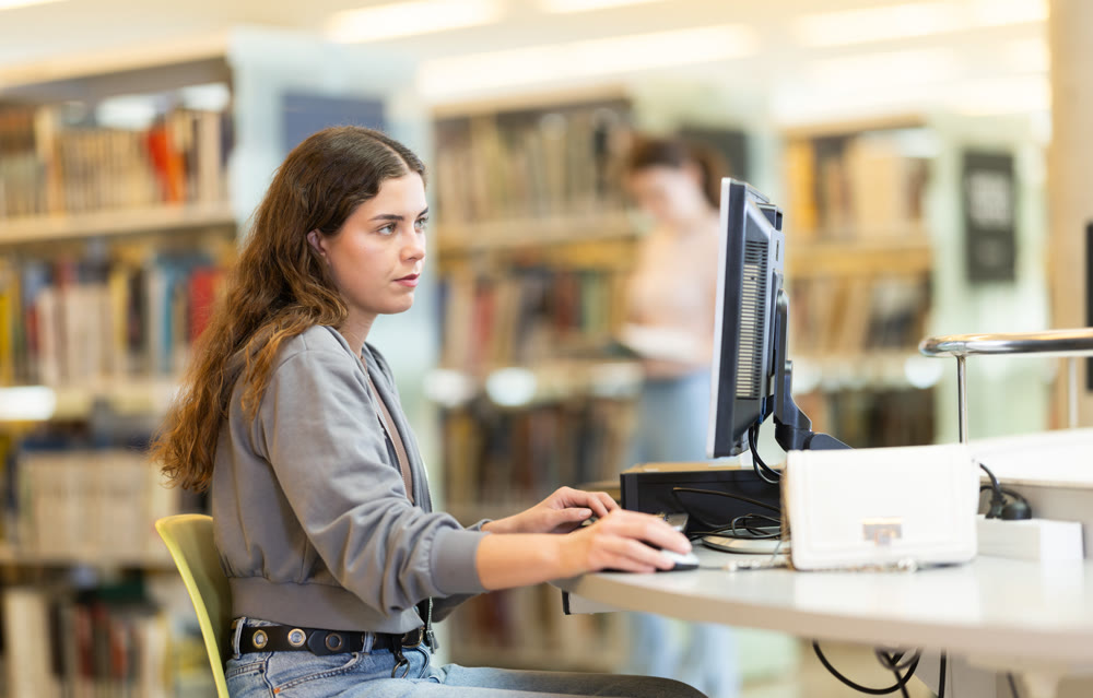 Girl searches for information on the internet using computer in university library