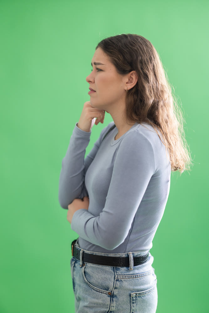 Young woman sad and upset in front of green screen