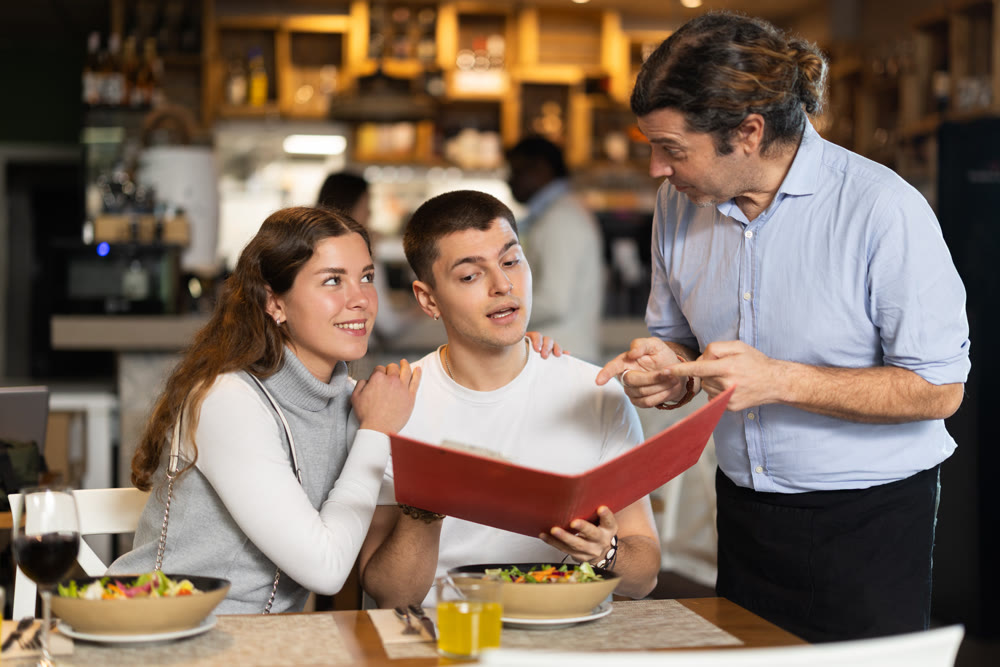 Man listen to restaurant couple customer, writes down order