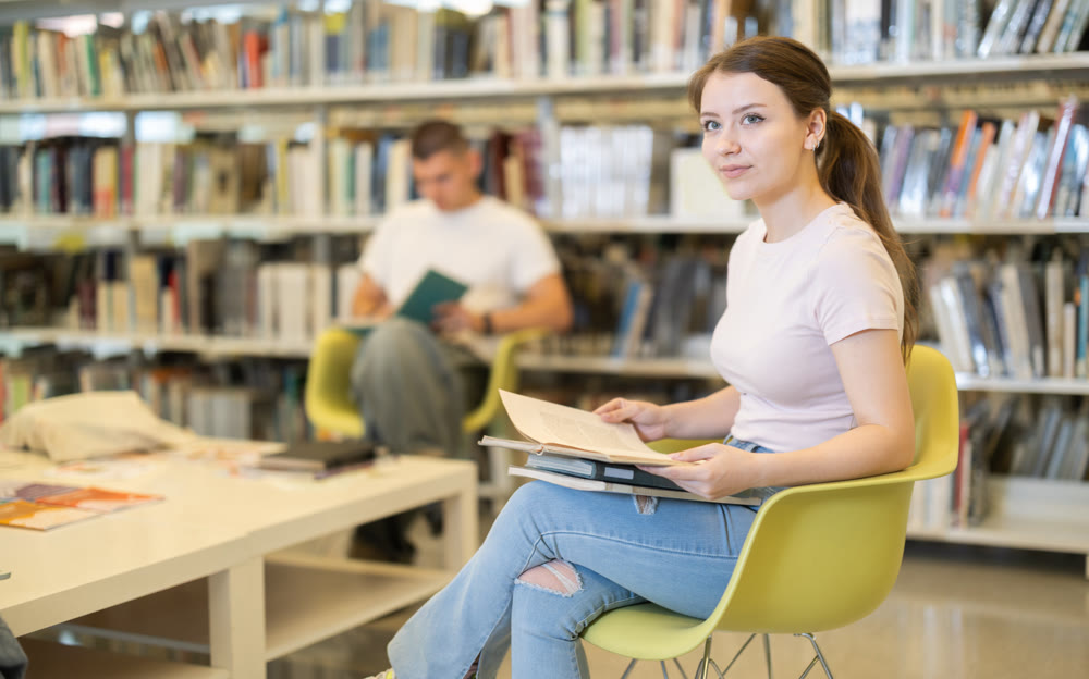 Female sitting on a chair in the library against the background of students