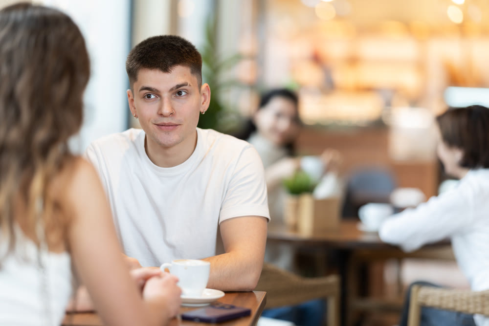 Guy in cafe sits opposite female companion, has nice conversation