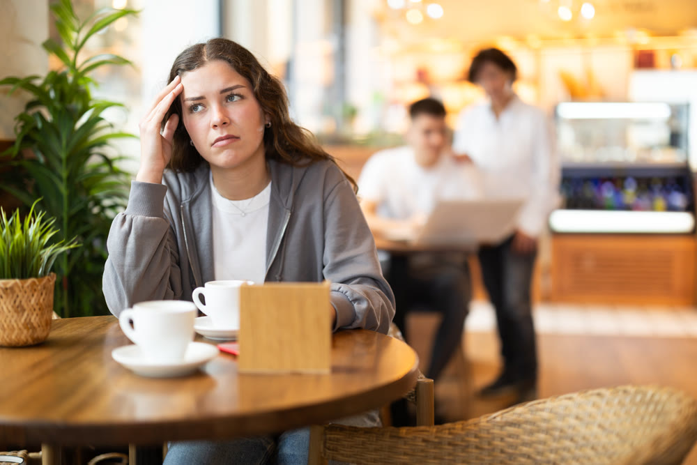 Sad young woman at table in cafe