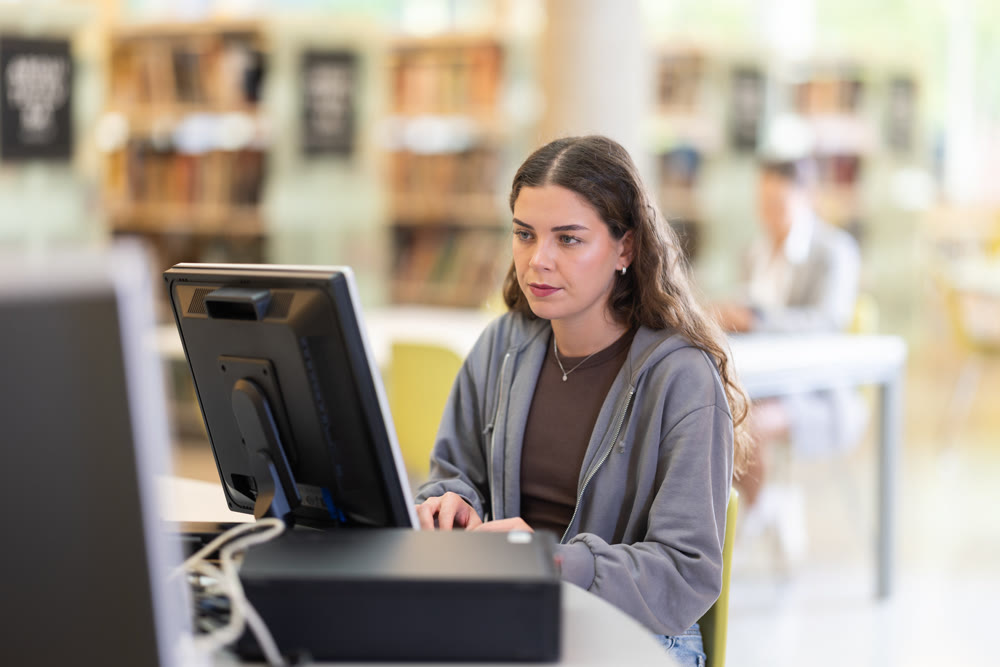Female student works at computer in library