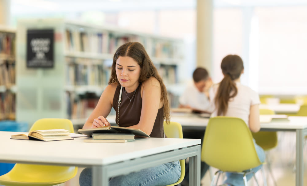 Female student sitting at table and writing