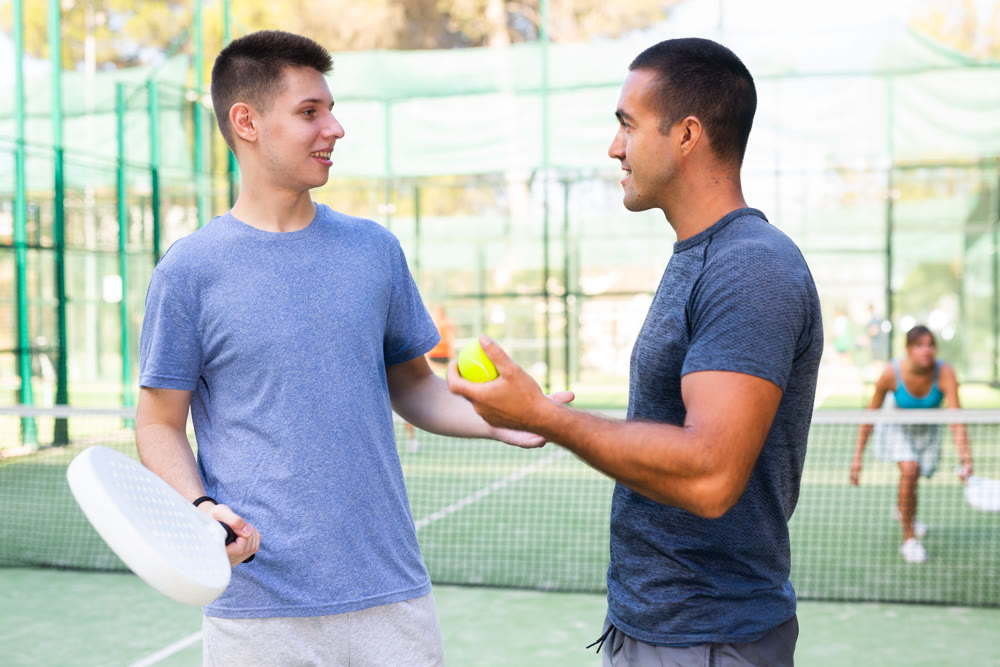 Men chatting on outdoor padel tennis court