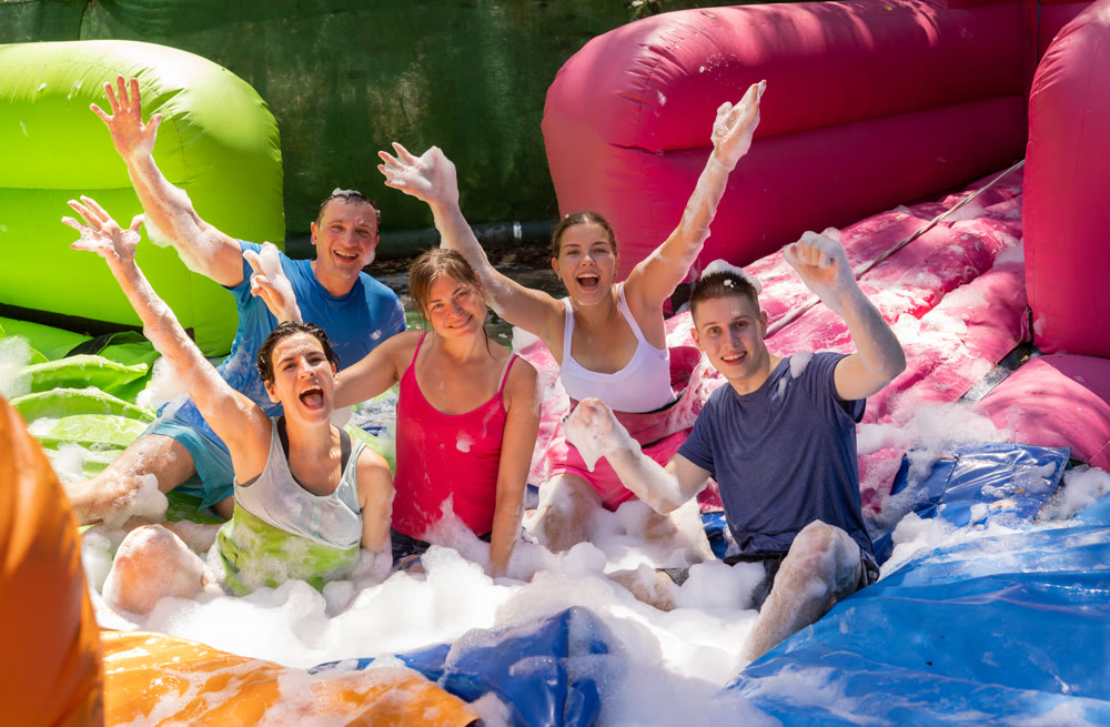 Cheerful men and women playing in foam pool in amusement park