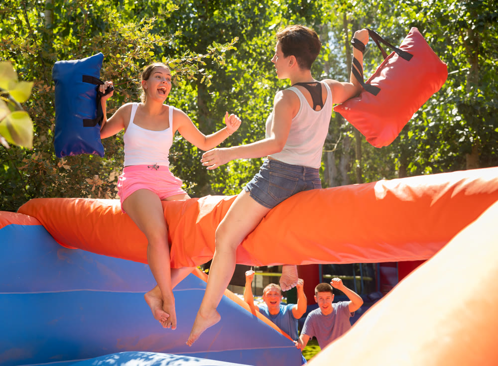 Women holding soft pillows and fighting in adventure park
