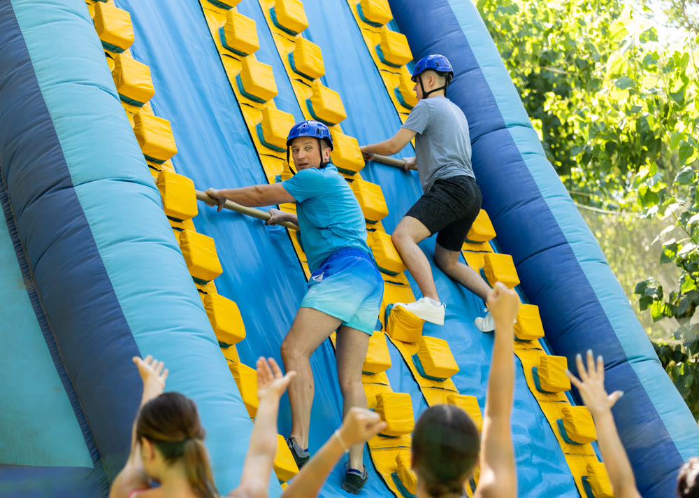 Father and son trying to climb on top of slide in amusement park