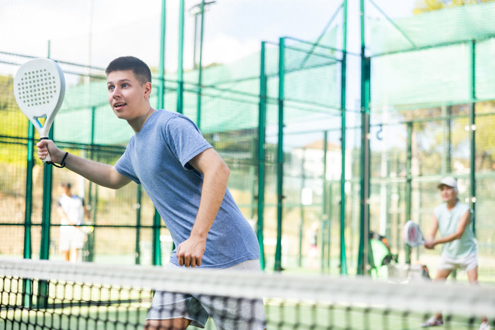 Young man playing padel tennis on court