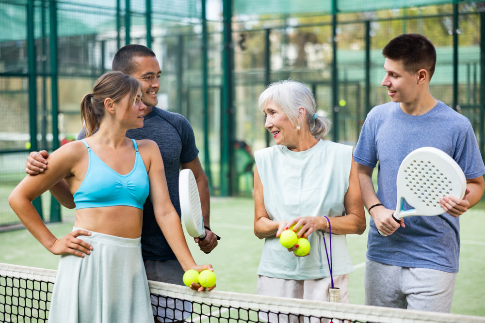 Group of cheerful paddle tennis players talking on open court