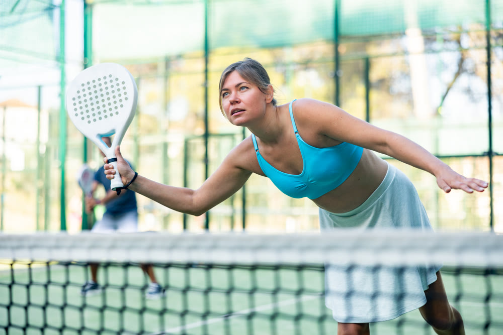 Padel game - woman with partners plays on tennis court
